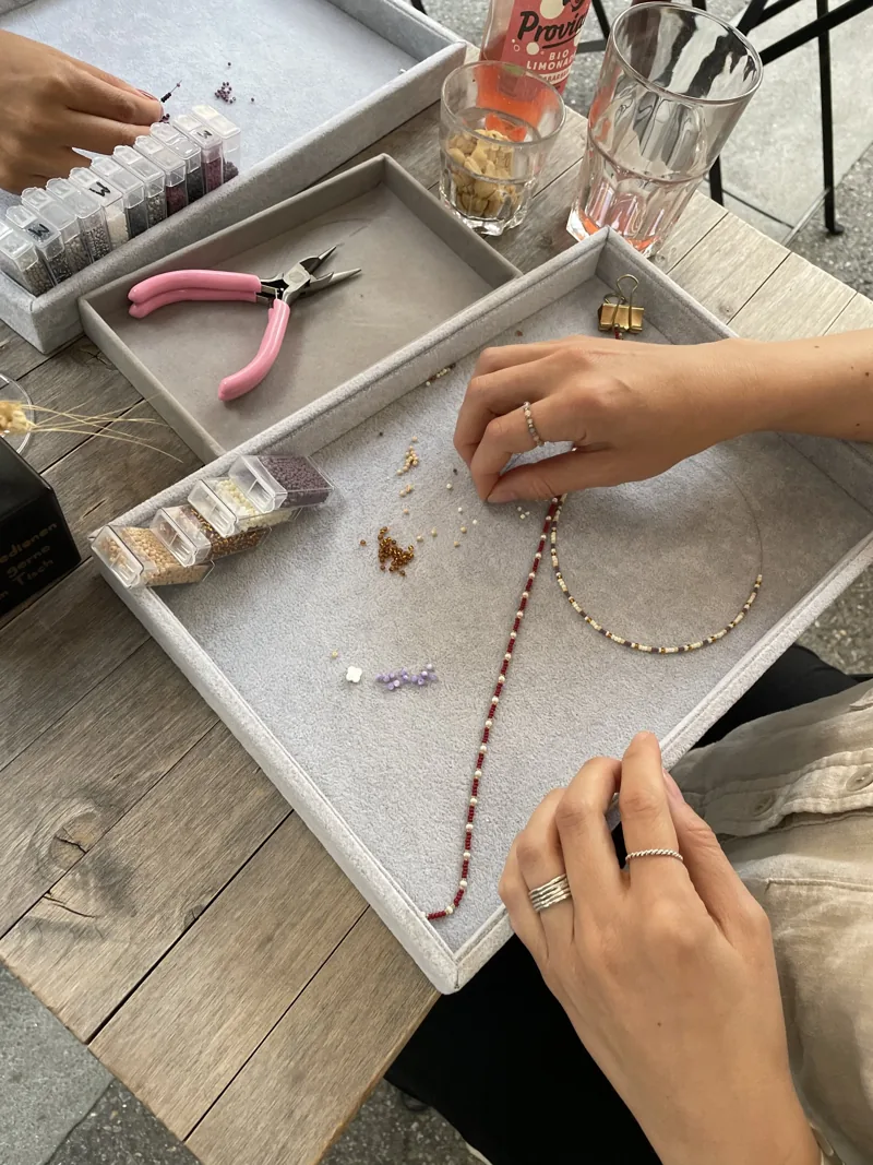 Bunte Perlen und selbstgemachter Schmuck auf einem Workshop-Tisch